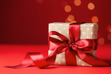 Sevgililer Günün kutlu olsun. Kırmızı arka plandaki hediye kutusu bulanık ışıklara karşı, yakın plan. Metin için boşluk