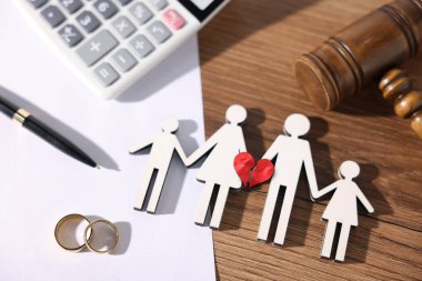 Boşanma ve nafaka kavramı. Aile figürü kırık kalp, alyans, hesap makinesi ve yargıç tokmağı masada.