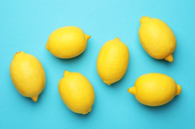 Açık mavi arka planda taze limonlar, düz uzanmış.