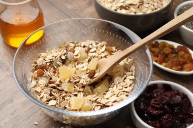 Tahıl yapıyorum. Tahta masada kurumuş meyveli yulaf gevrekleri, yakın plan.