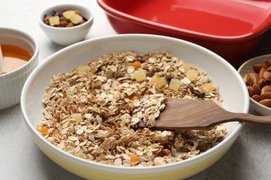 Tahıl yapıyorum. Bir kase yulaf ezmesi, bal ve kuru meyveler açık gri masada, yakın plan.