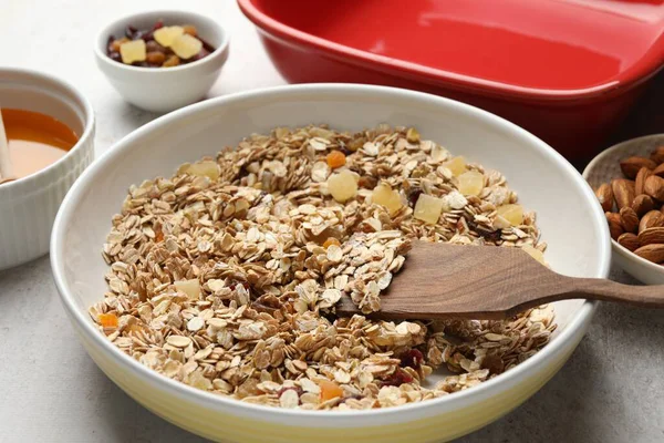 Tahıl yapıyorum. Bir kase yulaf ezmesi, bal ve kuru meyveler açık gri masada, yakın plan.