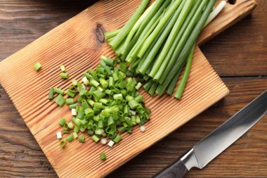 Tahta masada yeşil soğan ve bıçak kes, düz yat.