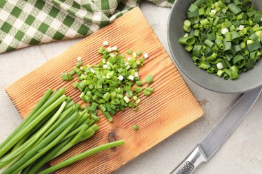 Açık gri masada yeşil soğan ve bıçak kes, düz yat.