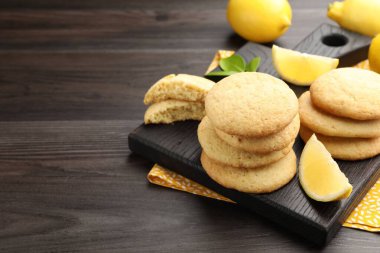 Lezzetli limonlu kurabiyeler ve koyu ahşap masada meyve dilimleri, yakın plan. Metin için boşluk