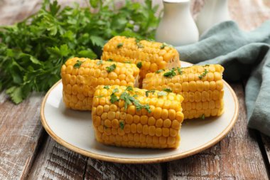 Ahşap masada maydanozlu haşlanmış mısır koçanı parçaları, yakın plan.