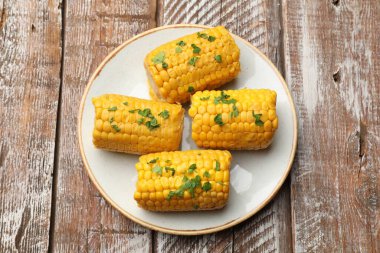 Ahşap masada maydanozlu haşlanmış mısır koçanı parçaları.