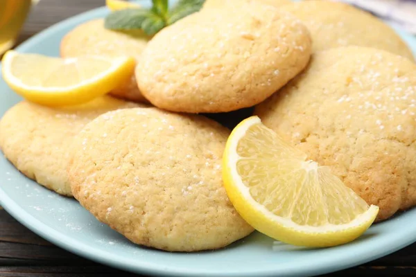 Lezzetli limonlu kurabiyeler ve siyah ahşap masada meyve dilimleri, yakın plan.