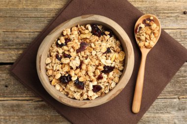 Lezzetli tahıl gevreği, kuru meyveler kasede ve kaşık tahta masada, düz uzanmış.