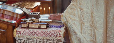 Rahip kilisede dini eşyalarla vaftiz töreni düzenliyor, yakın plan.