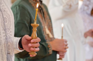 Kilisedeki vaftiz töreninde elinde mum tutan insanlar, yakın plan.