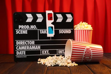 Kağıt bardaklarda lezzetli patlamış mısır, kağıt bardaklar ve kırmızı perdelere karşı ahşap masada 3 boyutlu bardaklar.