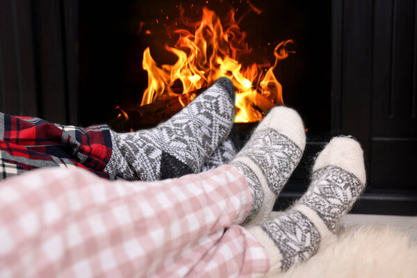 Couple in pajamas near fireplace at home, closeup. Winter season
