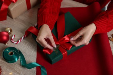 Noel hediyesini ahşap masaya paketleyen kadın, yakın plan.