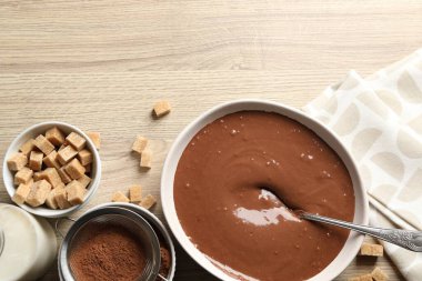 Kase içinde sıvı çikolata hamuru, kakao tozu, kahverengi şeker ve süt ahşap masada, düz yatak. Metin için boşluk