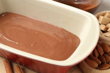 Liquid chocolate dough, brown sugar, cinnamon and nuts on table, closeup
