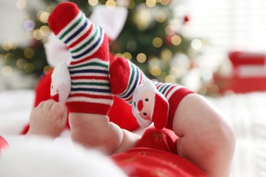 Noel çoraplı bebek. Yatakta. Kapalı alanda bulanık ışıklara karşı.