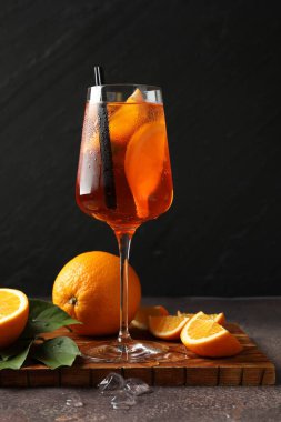 Gri masada tazeleyici spritzer kokteyli, buz küpleri ve portakallar.