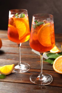 Serinletici spritzer kokteyli ve portakallar ahşap masada.