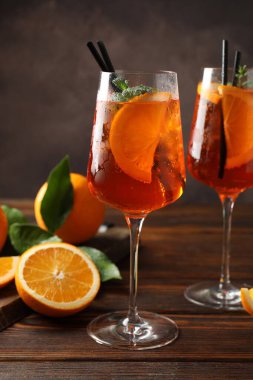 Serinletici spritzer kokteyli ve portakallar ahşap masada.