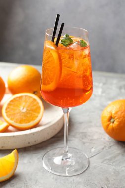Gri desenli masaya serinletici bir kokteyl ve portakallar.