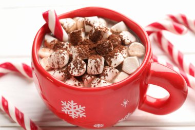 Marşmelovlu ve beyaz ahşap masada şeker kamışlı lezzetli kakao, yakın plan. Noel atmosferi