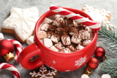 Marşmelovlu lezzetli kakao, baston şekerler, zencefilli kurabiyeler ve gri masada Noel dekoru, yakın plan.