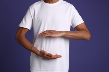 Mor arka planda sağlıklı midesi olan adam, yakın plan.