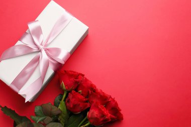 Güzel bir hediye ve kırmızı arka planda güller, metin için yeri olan düz bir yer. Sevgililer Günü