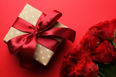 Güzel bir hediye ve kırmızı arka planda güller, düz yatış. Sevgililer Günü