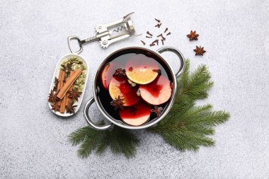 Geleneksel sıcak şarap demlikte, tirbuşonda, baharatlarda ve köknar dallarında açık gri masada, düz yerde.