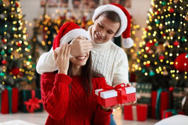 Mutlu erkek arkadaşı evde Noel hediyesiyle kız arkadaşına sürpriz yapıyor.