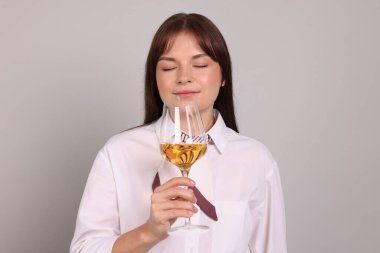 Profesyonel şarap garsonu açık gri arka planda beyaz şarap tadıyor.