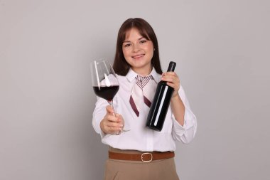 Açık gri arka planda kırmızı şarap ve şişe ile profesyonel şarap garsonu.