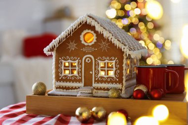 Güzel zencefilli kurabiye evi, kupalar ve takılar kapalı mekândaki bulanık ışıklara karşı, yakın çekim. Noel atmosferi