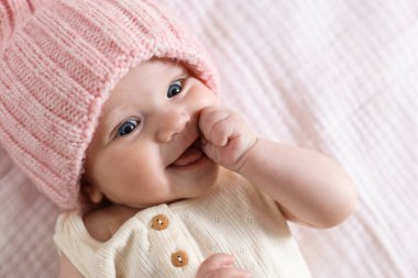 Yatakta örülmüş şapkalı şirin bir bebek.