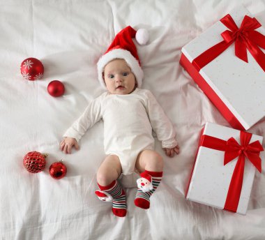 Noel Baba şapkalı bebek, Noel hediyeleri ve yatakta takılar, üst manzara.