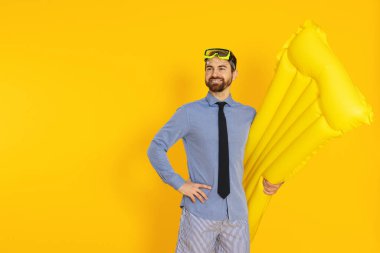 Dalış maskesi ve turuncu arka planda şişme yatağı olan bir iş adamı.