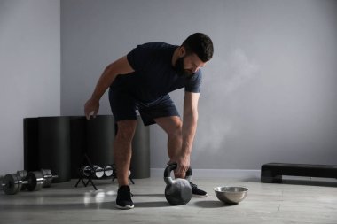 Spor salonunda kettlebell ile egzersiz yapan güçlü bir adam.