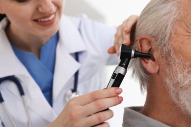 Duyma testi. Klinikte otoskopla hastanın kulağını muayene eden doktor, yakın plan.