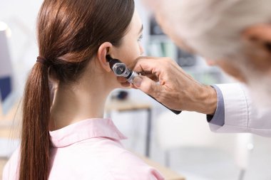 Duyma testi. Klinikte otoskopla hastanın kulağını muayene eden doktor, yakın plan.