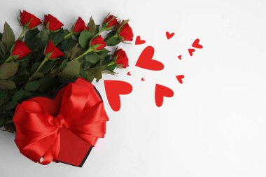 Kırmızı gül buketi, hediye kutusu ve beyaz arka planda kalpler, üst manzara. Romantik tebrik kartı.