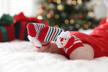 Noel çoraplı bebek. Yatakta. Kapalı alanda bulanık ışıklara karşı.