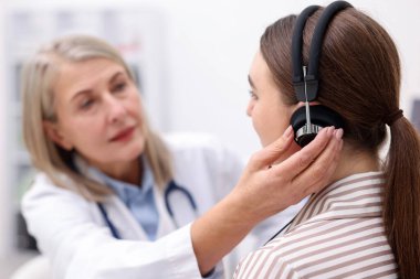 Duyma testi. Doktor klinikte hastanın işitsel kulaklığını ayarlıyor.