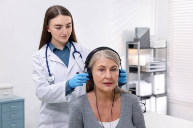 Duyma testi. Doktor klinikte hastanın işitsel kulaklığını ayarlıyor.