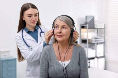 Duyma testi. Doktor klinikte hastanın işitsel kulaklığını ayarlıyor.