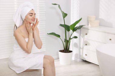 Saçları havluya sarılı bir kadın, mesaj atmak için yer.