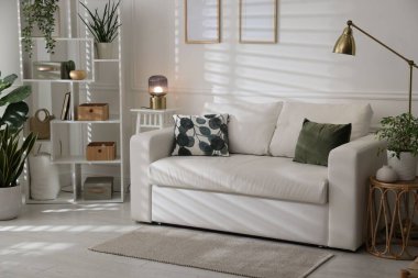 Rahat bir kanepe, diğer mobilyalar ve kapalı alandaki yeşil bitkiler. İç tasarım