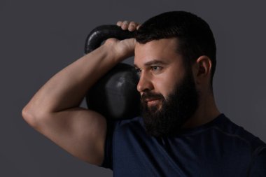 Gri arka planda kettlebell ile egzersiz yapan adam.