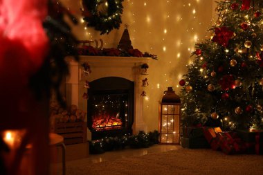 Güzel bir şömine, Noel ağacı ve karanlık odada şenlikli bir dekor. İç tasarım